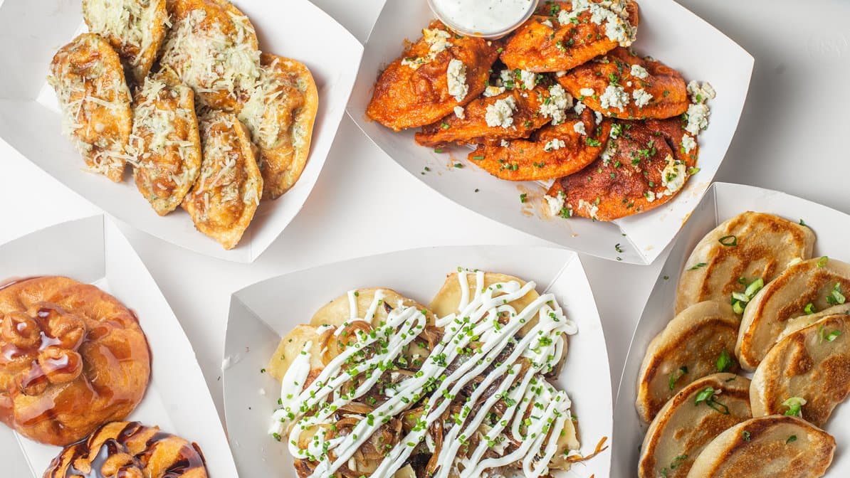 An overhead spread of pierogi, buffalo chicken dumplings, gyoza and a fried cheesecake bun