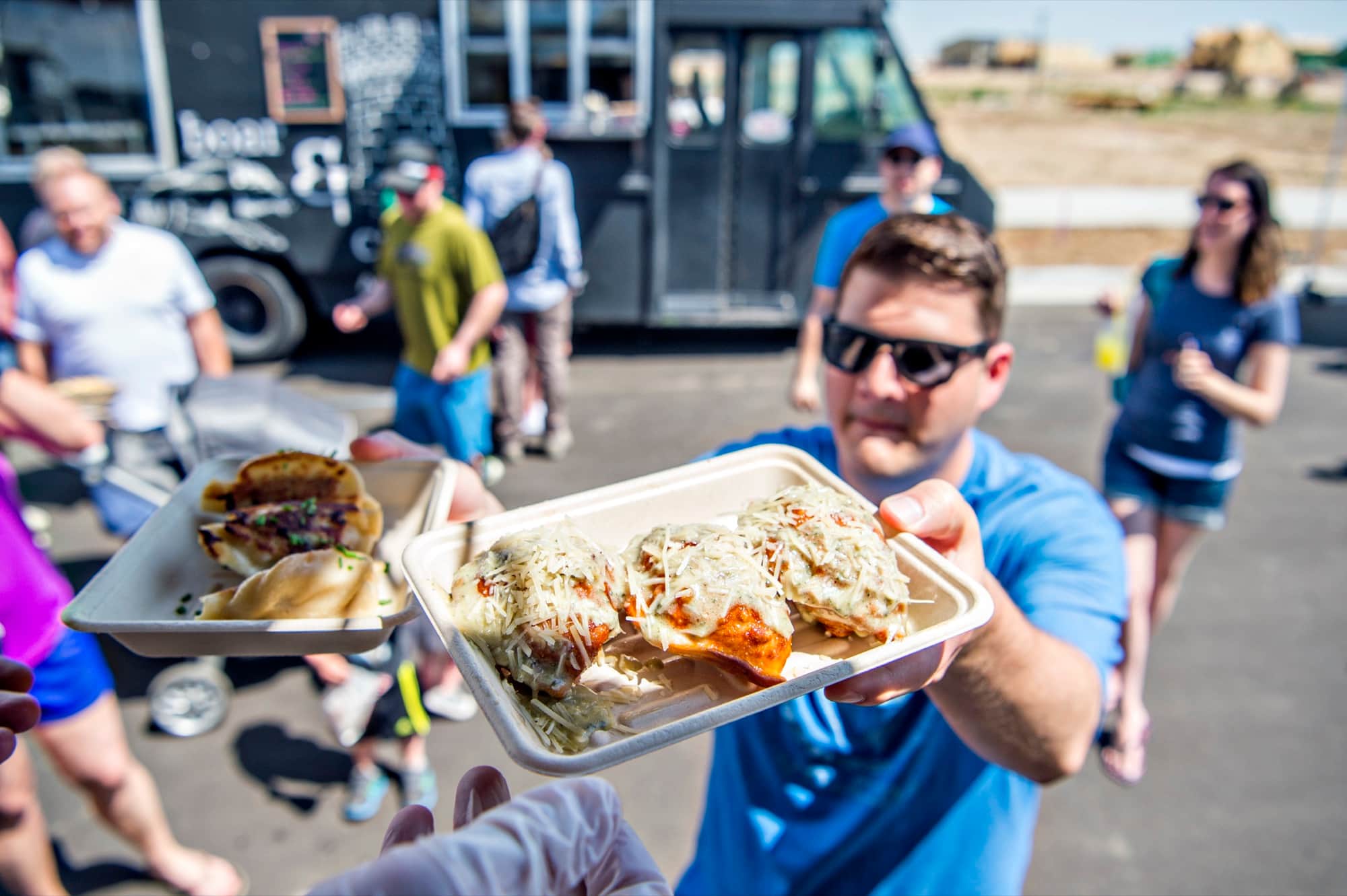 A guest holding a tray of dumplings in front of the truck